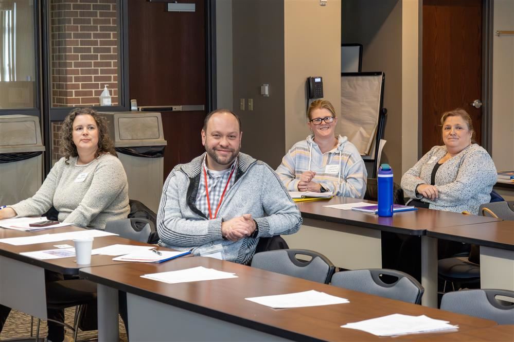  Four people are smiling after a presentation wraps up and questions are answered.